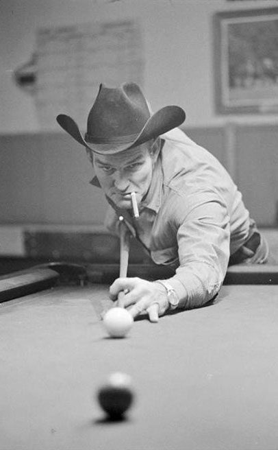 A man identified as Fuzz Tabor looks into the camera as he leans in for a pool shot at the Alpine Tavern, located in Alpine, Oregon., James Cloutier photographs, 1977