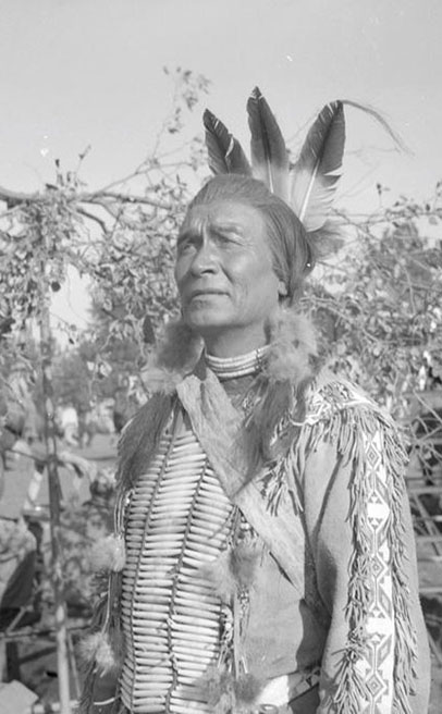 An outdoor portrait of a man, identified as John War Eagle, dressed in Native American regalia., Lee D. Drake (1882-1957) photographs, ca. 1910-1957