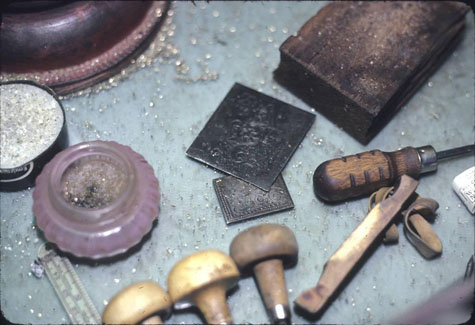 Engraving equipment in front of V., showing prized examples of other engravers' work, Northwest Folklife Digital Collection