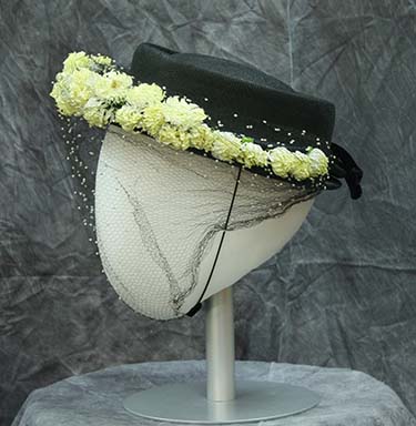 Hat of black straw with shallow crown and small front brim accented with yellow artificial flowers encased in tulle veil, Historic and Cultural Textile and Apparel Collection