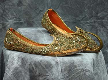 Slip-on shoes of orange silk heavily embroidered with metal coil, sequins, and mirrors in a flower and leaf design, Historic and Cultural Textile and Apparel Collection