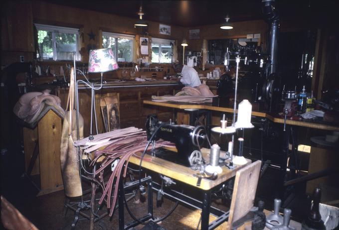 Elmer's shop, interior of work room, Elmer at counter carving leather