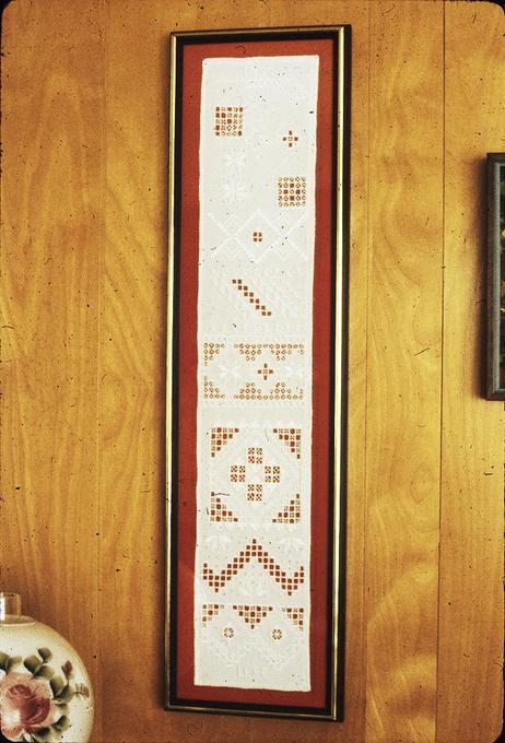 Sampler, framed and displayed in living room. Made by Mrs. Lee, her 'original idea' of how to get many patterns on a single piece, both for teaching others and for display. These are mostly her mother's patterns of Hardanger embroidery.