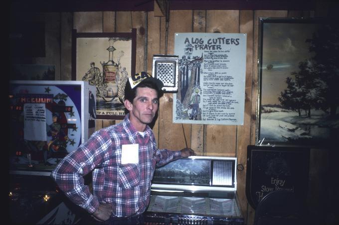 Mr. Walt Moore at juke box in front of his logger's poster
