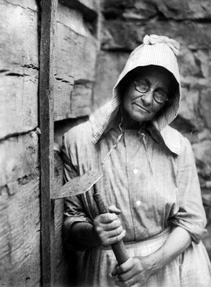Woman, wearing bonnet and glasses, with  hoe