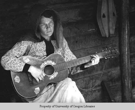 Anner Owenby, with guitar and dulcimer by cabin