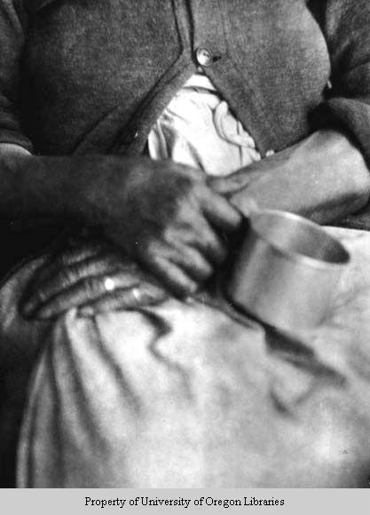 Hands of elderly African-American woman, holding tin cup