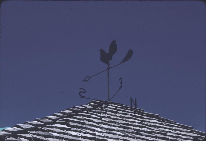 Cock weathervane atop roof, short view