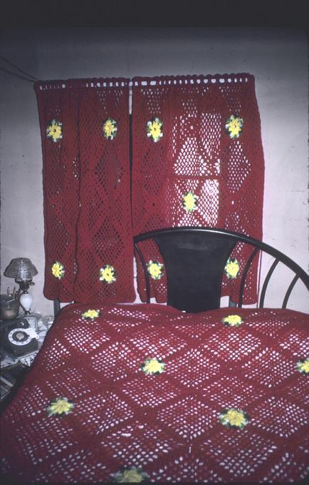 Crocheted curtains behind bed with crochet bedspread
