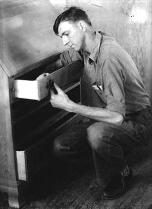 Victor McConkey, carpenter, inspecting cabinet drawers