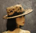 Hat of warm beige feathers with accents of black and brown feathers encased in grey net