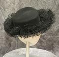 Hat of black wool felt with wide brim covered in bundles of net