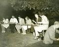 Group sitting in a yard eating watermelon