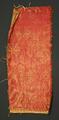 Textile fragment of red and gold heavy woven fabric with an ornate design