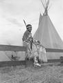Young Native American woman sitting on fence rail