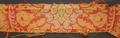 Textile fragment of red and yellow heavyweight woven fabric in a ornate floral design with bugle shapes
