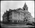 Washington High School, Portland. Stone building with bell tower. Street in foreground.