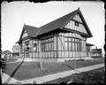 Exterior of Gresham Library. Brick and timber building, seen from corner. Sidewalk in foreground.