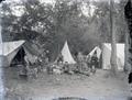 Family group camping with child sitting in a Studebaker toy wagon