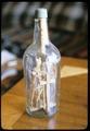 11 x 5 inch whiskey bottle with carvings inside (including 27 people): with bows and arrows, 1 person with an axe, 1 cross, 1 tree/fan, 1 yoke with hanging links