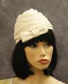 Turban-style hat of shimmery ivory fabric woven to a peak at top with a half bow at front