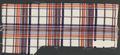 Textile sample of woven polyester yarns in white, navy, red, and yellow varied stripe plaid