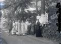 Group of women standing in road next to wooded hillside and posed in a garden?