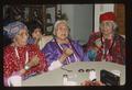 (Master Singer) Matilda Mitchell sits at table with her 2 sisters (Washaat religious singing)