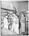 Students helping to clean up City Hall Pharmacy after fire, February 1956