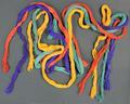 Hair accessory of four cords of cotton net in turquoise, purple, yellow, and red with knotted and braided ends with fringe