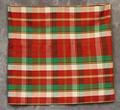 Skirt of a sewn tube shape in red, white, green, yellow, and black plaid patterned cotton with a 6" stitched hem