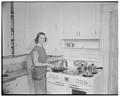 A student cooking in a home management house, 1953