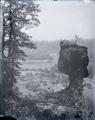 Rock formation above railroad and farm, next to a river