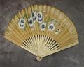 Folding fan of blond wood mounted with beige paper painted with blue and white flowers and green leaves