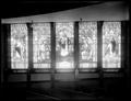 Interior of First Congregational Church, Portland, showing row of stained glass windows separated by columns. Row of pews in foreground.