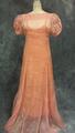 Dress of salmon organdy has bateau neckline and short puffy sleeves