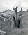 Agricultural laborers treating fence posts