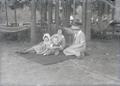 Two women and two children sitting on blanket under trees