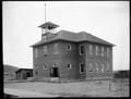 Public school, Grainger, WA., surrounded by bare yard. Board sidewalk around building.