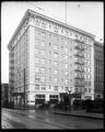 Imperial Hotel, Broadway and Stark, Portland. Autos parked on street. Fence in foreground.