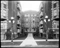 Front view, Trinity Place Apartments. Walkway from street to door. Curb and streetlamps in foreground.