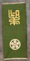 Tapestry of green heavy-weight ribbed woven silk with a white medallion emblem and a gold Japanese character