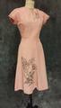 Dress of pink rayon faille with stenciled design of stemmed flowers of skirt and bell flowers on bodice and linear pattern on cap sleeves