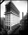 Northwestern National Bank, Portland, corner of 6th NW and Morrison, under construction. Scaffolding on building, structural support visible. Building materials and Dinwiddie Construction Co. sign in foreground.