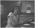 Portrait of an unidentified woman (Summer Session faculty member?) seated at a desk and holding a pencil