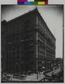 Chamber of Commerce at 5th and Stark, Portland. Autos and wagons on street, traffic policeman at intersection in foreground. (recto)