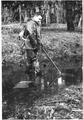 Man with equipment on back standing in river