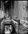 Interior view of Forestry Building on Lewis & Clark Exposition site, from top of stairway. Part of floor visible below. Large log support beams in foreground.