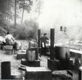 Outdoor kitchen set up with steaming pots, female cook