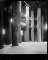 Interior floor view of Forestry Building, on grounds of Lewis & Clark Exposition, Portland. Two men standing beneath large wooden support beams.